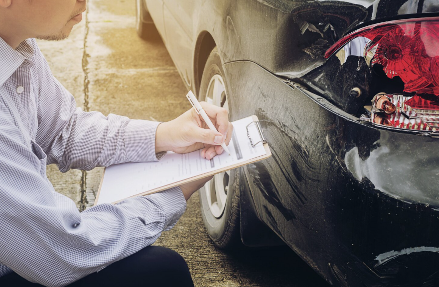 insurance adjuster inspecting vehicle damage during insurance claims evaluation